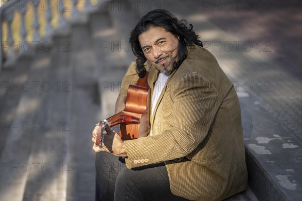 Flamenco guitarist sitting on some stairs performing