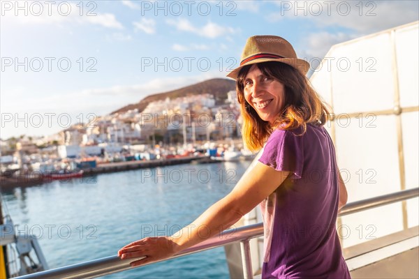 A female tourist from the Ferry and the city of Los Cristianos in the background on the island of Tenerife. Ferry coming from La Gomera