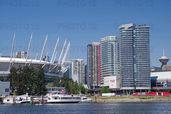 Small boats in front of yachts and skyscraper canyons and Olympic Stadium