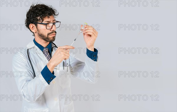 Young doctor drawing medicine from a vial with copy space. doctor drawing medicine from a vial. Concept of doctor with disease antidote