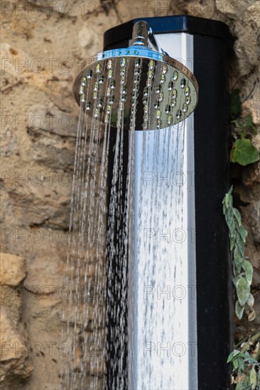 Shower in the street over a stone wall spraying water