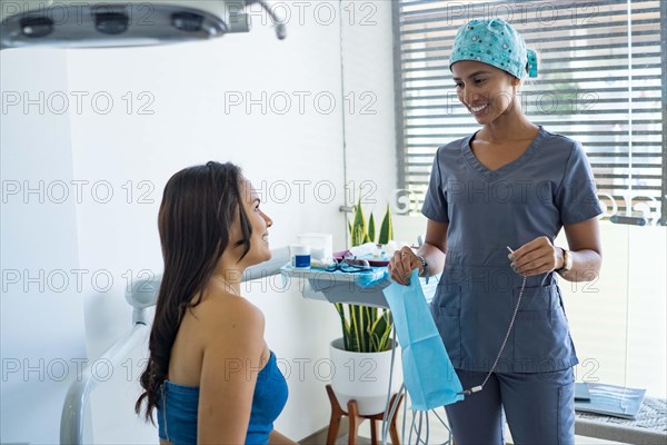 Female dentist in dental office talking with female patient and preparing for treatment. Concept of whitening