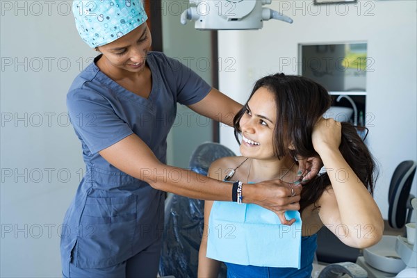 Beautiful young woman in dentist office smiling and looking at her orthodontist. Concept of whitening