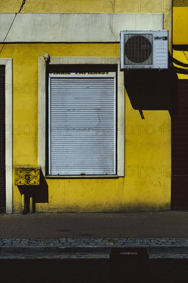 Yellow wall with closed shop blinds