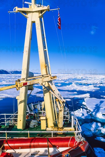 Ship on the way in ice on the rocky coast of Svalbard