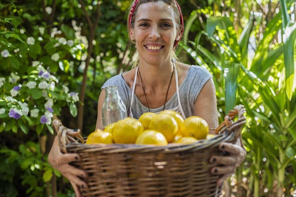 A woman showing a big basket full of fresh lemons