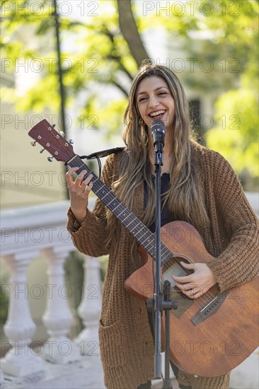 Young blonde woman playing the guitar and singing in the street