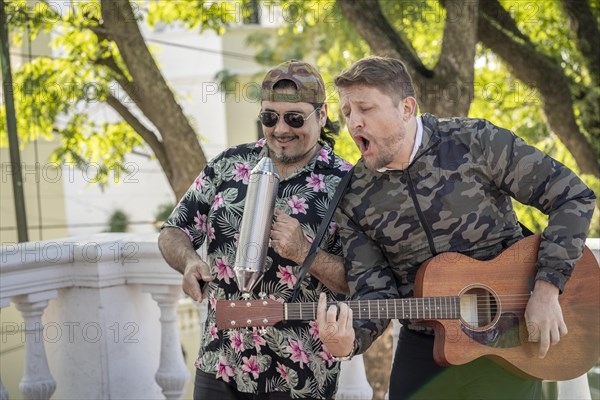 Street band performing at the street. Musicians palying guitar and gueiro