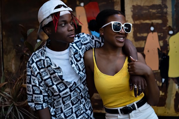 Young African American couple enjoying themselves. He embraces her and they both look to the side. Both dressed in modern clothes