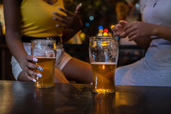 Two friends drinking beer. Detail shot of beer glasses without faces. Unrecognized people