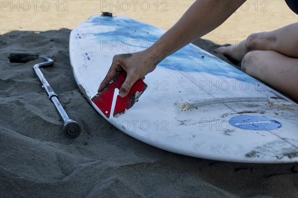 Detail shot of young woman preparing her board for adapted surfing competition