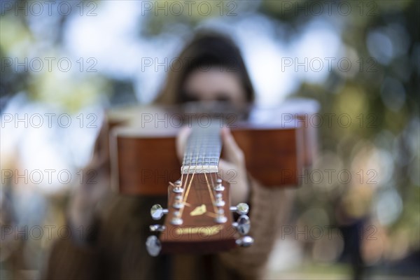 Woman pointing her guitar to the camera. Inspirational concept