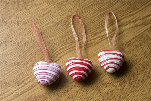 3 pendants in heart shape on wooden plate for decoration