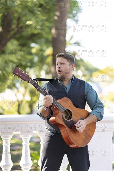 Musician man playing guitar and singing in the street