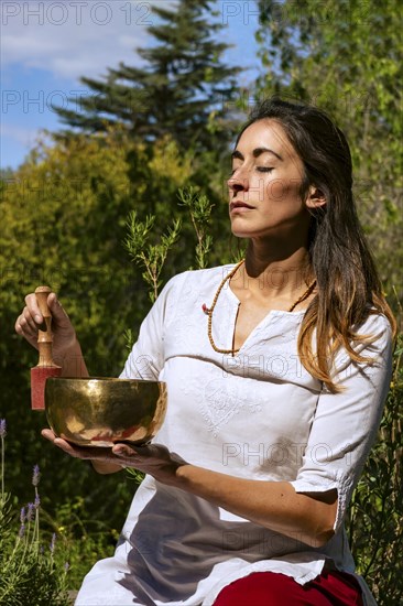 Woman playing a Tibetan singing bowl outdoors. Sound therapy