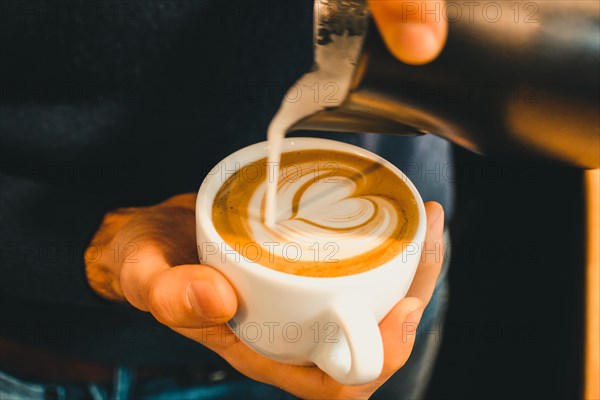 Frothed milk is poured into a coffee cup to the heart