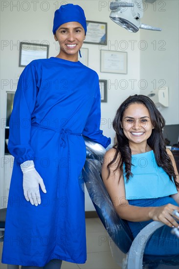 Beautiful woman sitting in the dentist chair with her dentist smiles looking at the camera