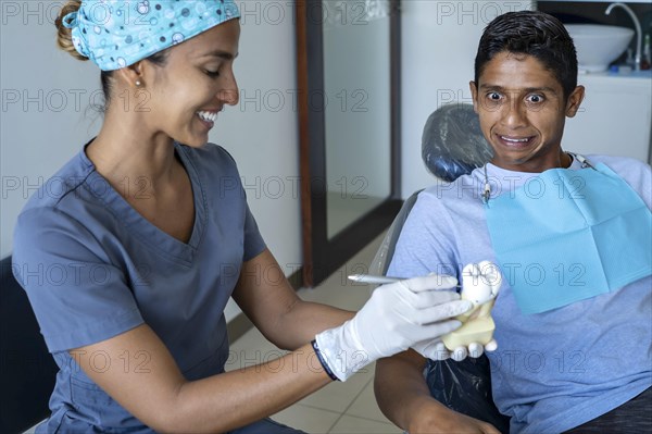 Young male patient visiting dentist office. Short Hair man with healthy straight white teeth sitting at dental chair and waiting his doctor. Dental clinic background for copy space text