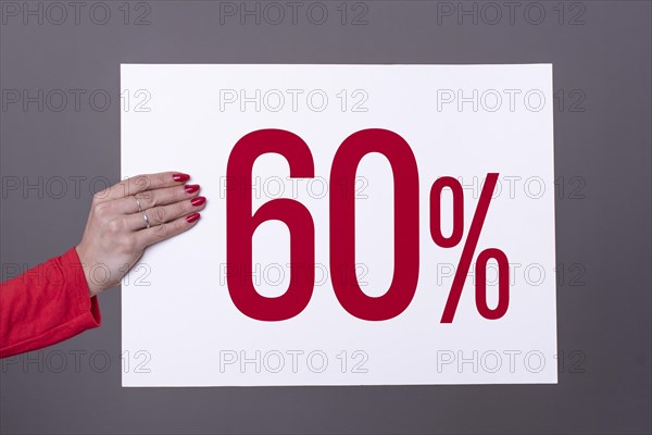 Female hand holding a 60% poster. Studio shot. Commercial concept