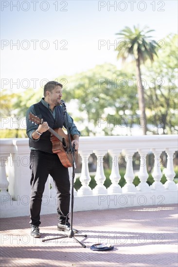 Musician man playing guitar and singing in the street