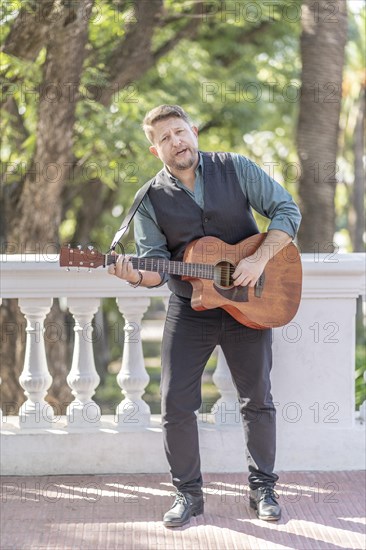 Musician man playing guitar and singing in the street