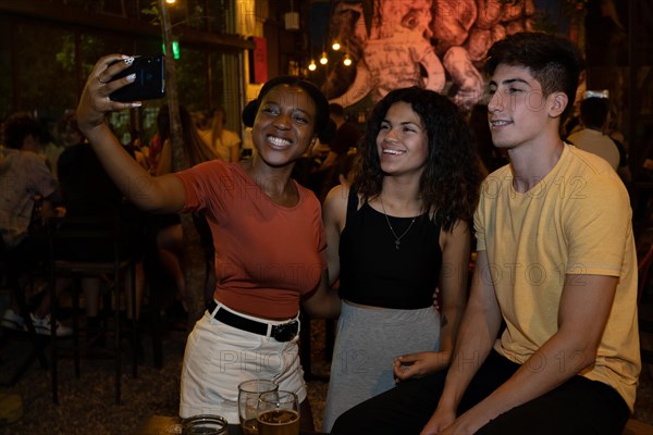 Group of friends taking self portrait in bar with flash. Multiethnic concept