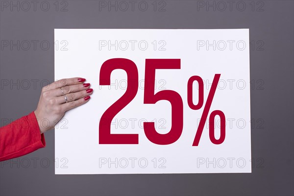 Female hand holding a 25% poster. Studio shot. Commercial concept