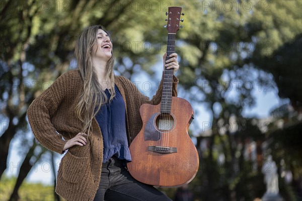 Young blonde woman with her guitar in the park. Concept of creative hobbiess and professionals. Positive attitude. Empowerment