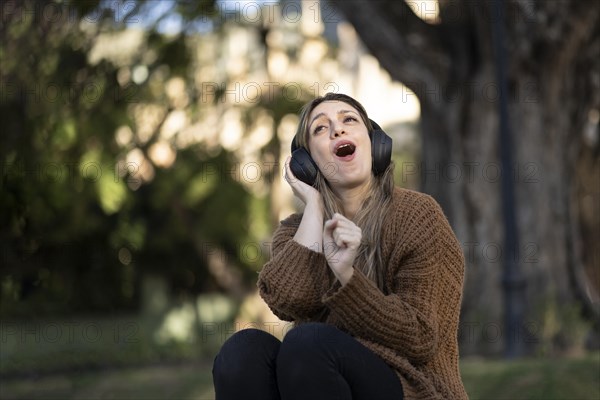 Blonde woman sitting on the street listening to music