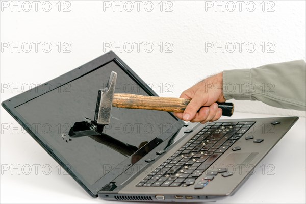 Arm of a man breaking a laptop with a hammer isolated on white background and copy space