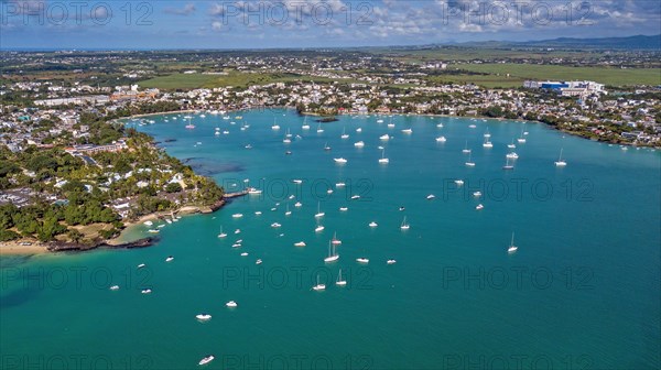 Aerial view from bird's eye view of large sea bay Grand Baie with pleasure boats motor yachts sailboats anchored in sheltered bay