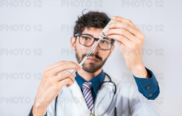 Doctor drawing medicine from a vial isolated. Young doctor drawing medicine from a vial with copy space. Concept of doctor with disease antidote