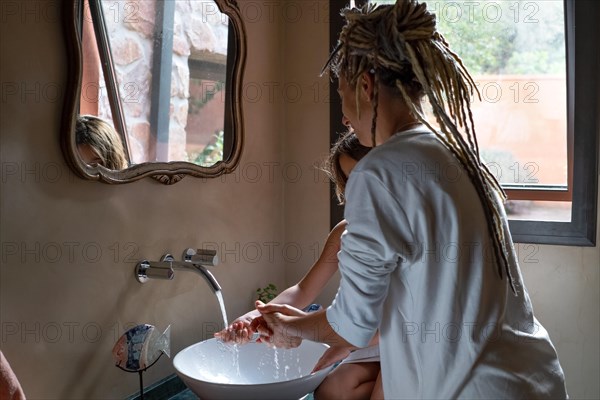 Mother and daughter wash their hand together in the bathroom sink. Design bathroom. Motherhood concept