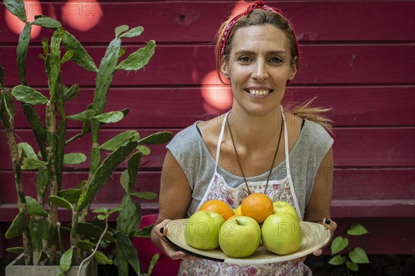 A woman carring a plateb full of fresh citrus and apples