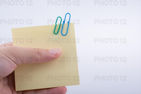 Hand holding a notepaper with paper clips on a white background