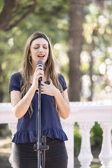Young blonde woman singing in the street. Singer performing in the street