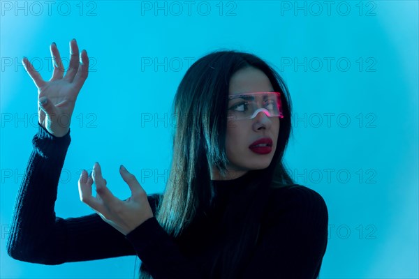 Metaverse technology concept. Woman in futuristic glasses on a blue background. Futuristic