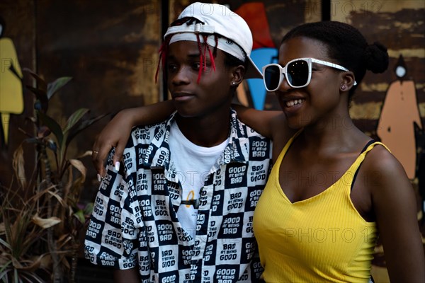 Positive African American youth hugging each other wearing fashionable clothes