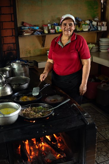 Mature latin woman cooking looks at the camera and smiles