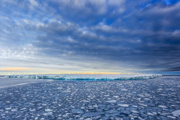 Giant iceberg floating in the Arctic sea surrounded by little icebergs