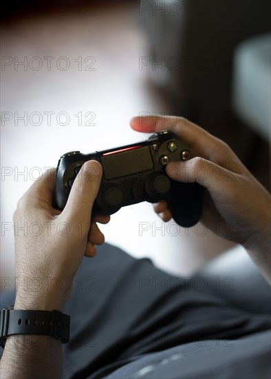 High angle view of an adult man's hands holding a joystick while playing a video game on a console