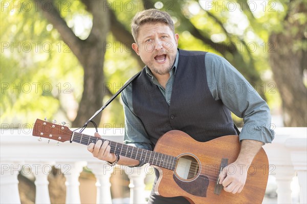 Musician man playing guitar and singing in the street