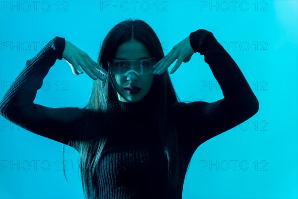 Metaverse technology concept. Portrait of woman in futuristic glasses with led light on a blue background