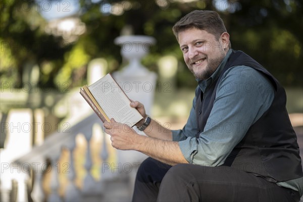 Business man reading a book in a park