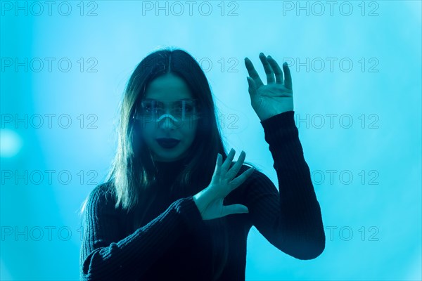 Metaverse technology concept. Woman in futuristic glasses with led light on a blue background. Futuristic