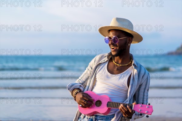 Portrait of black ethnic man enjoy summer vacation on the beach playing ukulele