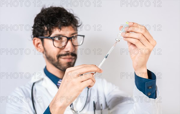 Handsome Doctor drawing medicine from a vial isolated. Young doctor drawing medicine from a vial isolated. Concept of doctor with disease antidote