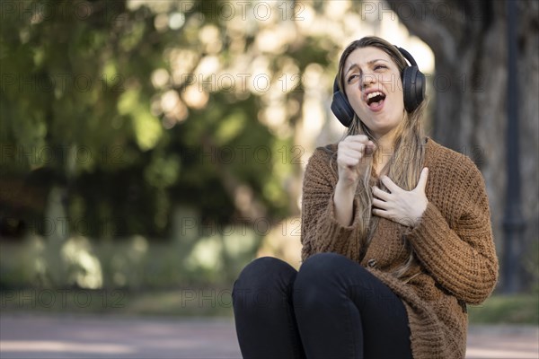 Blonde woman sitting on the street listening to music