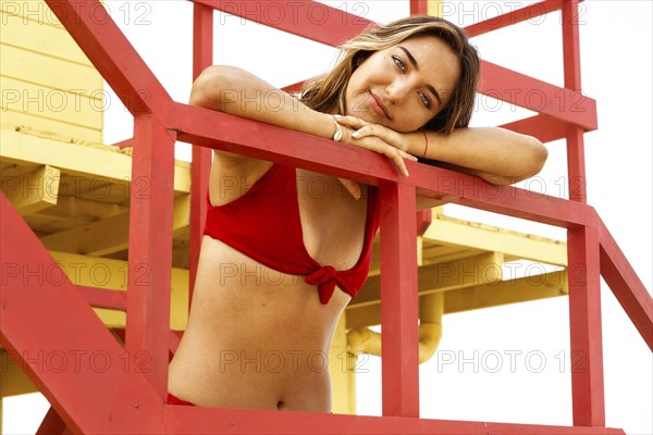 Young Latin beauty young woman in red bikini looking at camera in lifeguard booth