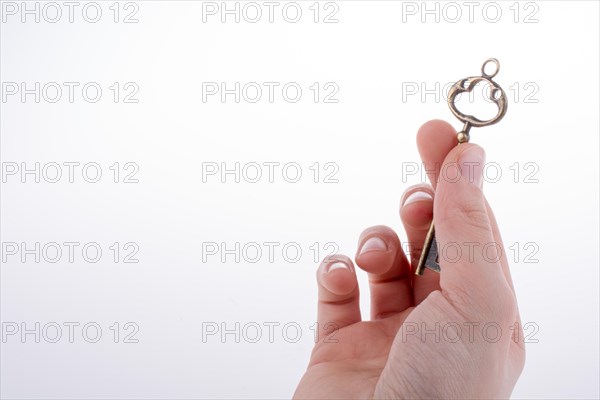 Hand holding a retro styled metal key on a white background